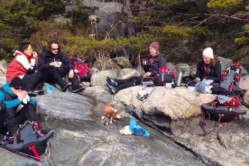 a group of people sitting on a rock having a break from ice skating
