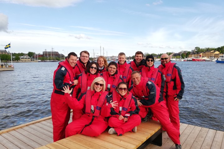 a group of people posing for a picture next to a body of water