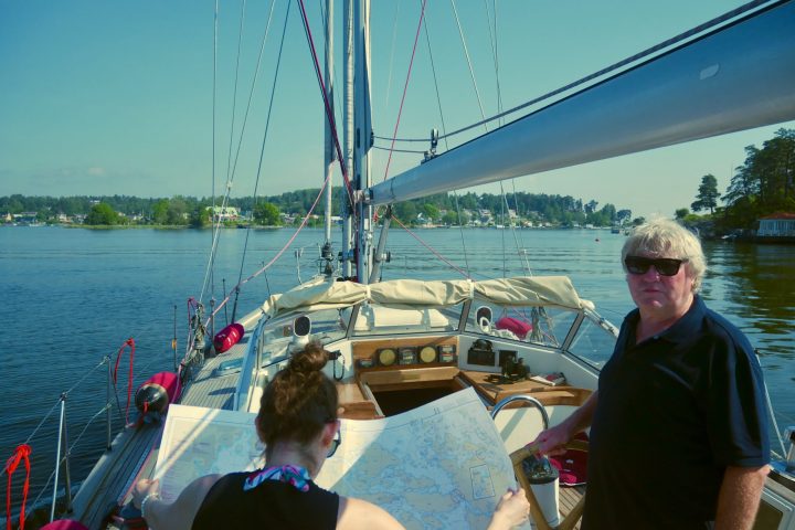 a man standing in front of a boat next to a body of water