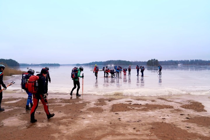 a group of people entering the frozen lake on a beach