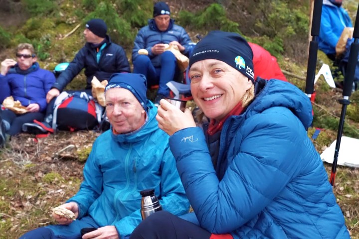 a group of people sitting in the grass on a break from ice skating