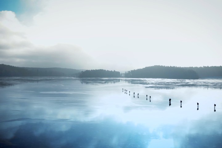 drop view of ice skaters crossing a lake