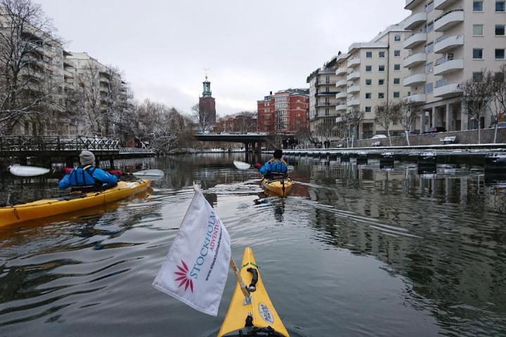 a kayak in a body of water with the Stockholm City Hall in the background