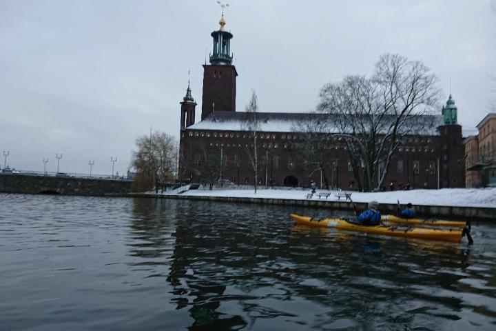 a person on a kayak in front of the Stockholm City Hall